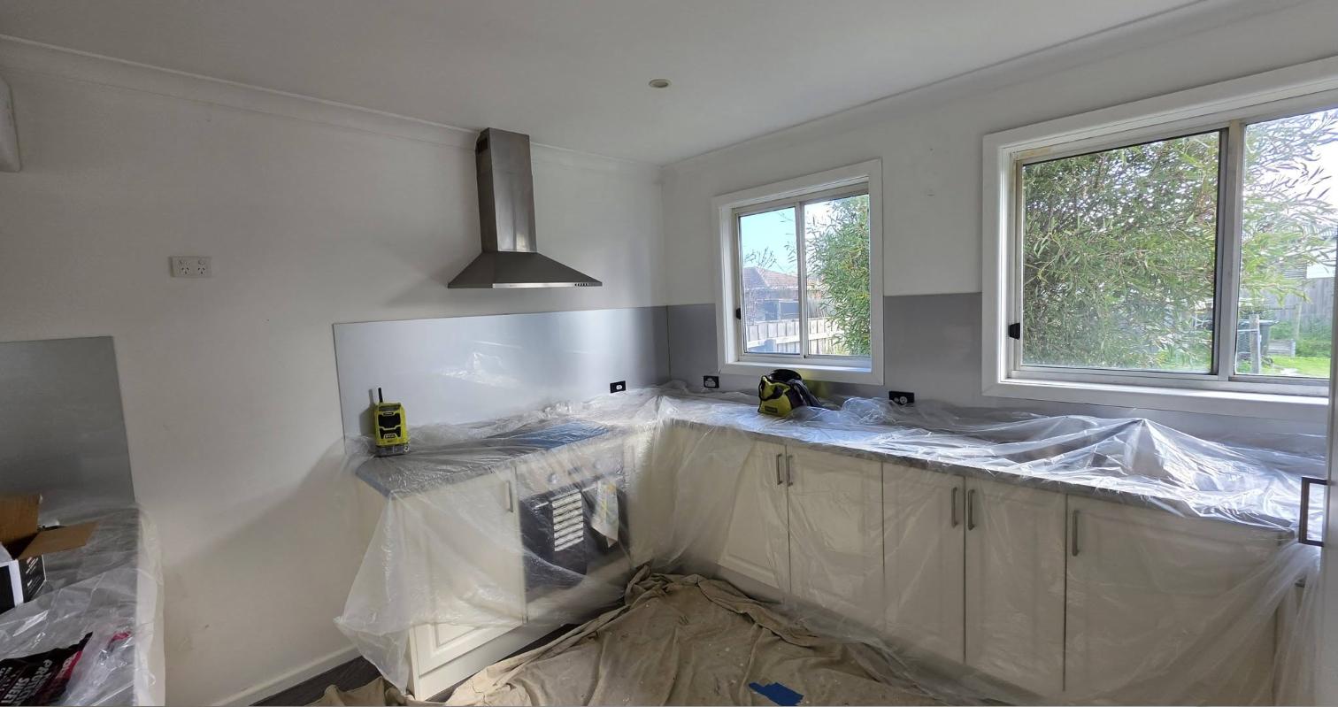 The same kitchen during the job, with plastic sheeting over the benchtop and cabinets