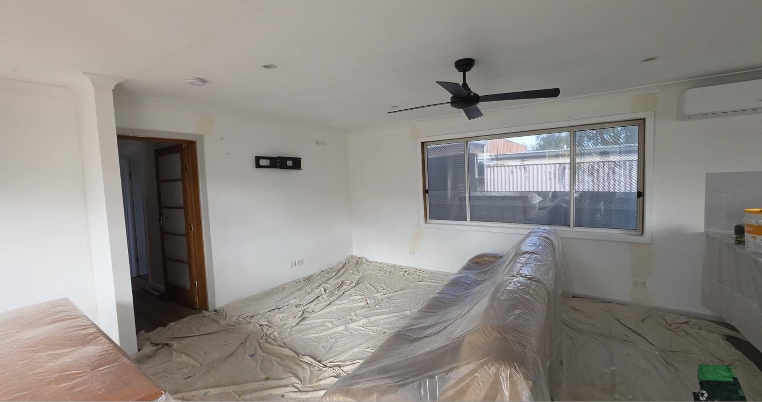 The same lounge room during the job, with drop sheets over the floor and couch